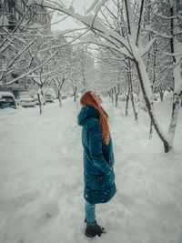 Rear view of woman standing on snow covered field