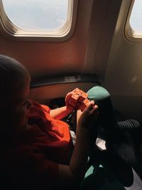 Side view of a boy with a toy in his hands sitting on an airplane
