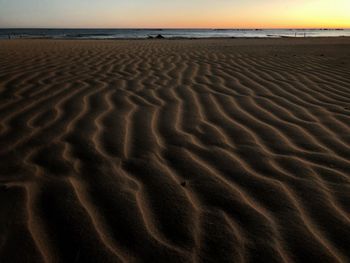 Footprints on sand at beach against sky