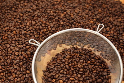 Full frame shot of coffee beans with colander on table