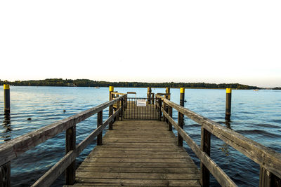 Pier over calm sea against clear sky