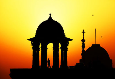 Silhouette of person standing at gazebo against sky during sunset