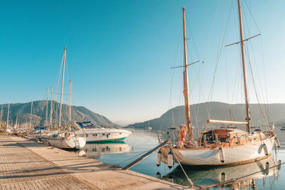 Boats in sea against clear blue sky