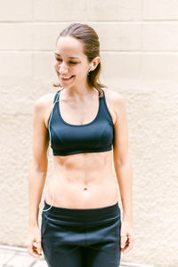 Portrait of young woman standing against wall