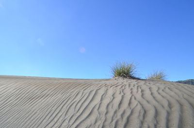 Scenic view of desert against clear blue sky