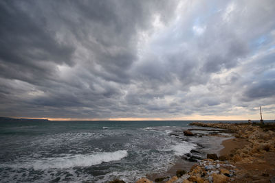 Scenic view of beach against dramatic sky