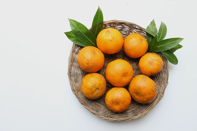 Picture of a fresh ripe yellow oranges in a wooden basket isolate on a white background