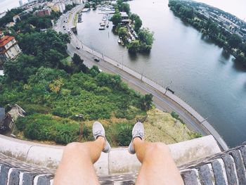 Low section of man relaxing on retaining wall by river