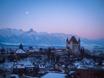 Historic castle in city against swiss alps in winter against clear sky