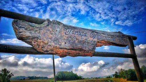 Low angle view of rusty metal hanging against sky