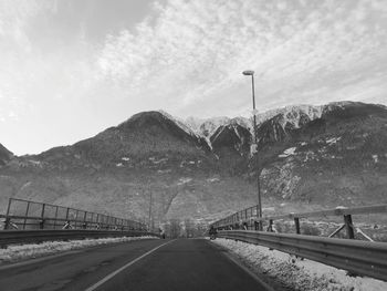 Empty road by mountains against sky