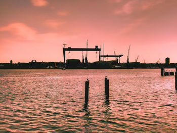 Sea by dock against sky during sunset