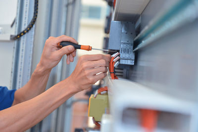 Cropped hands of electrician adjusting cables