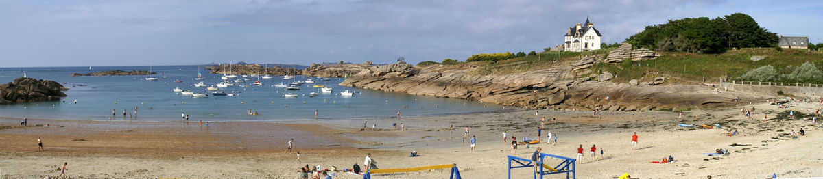 Panoramic view of people at beach against sky