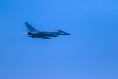 Low angle view of airplane flying against clear blue sky