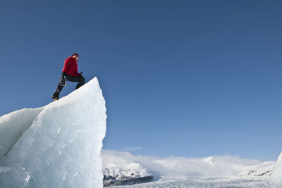 Woman climbinbg iceberg on the fjallsjoull glacier lagoon