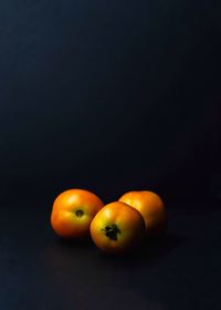 Close-up of orange fruits on table against black background