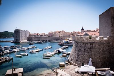 Boats moored in harbor against buildings in city