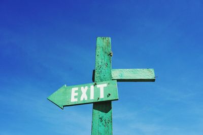 Low angle view of road sign against blue sky