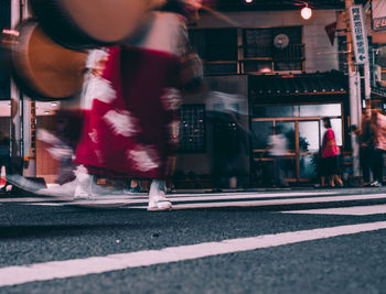 Low section of people walking on road in city