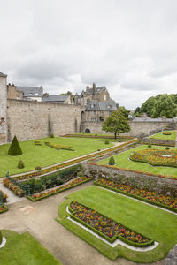 View of old building in garden against cloudy sky