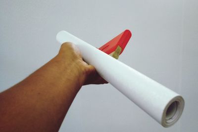 Close-up of hand holding paper over white background