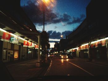 Road passing through illuminated city at night