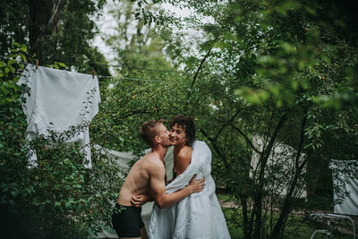 Young couple standing against trees