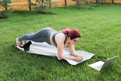 High angle view of woman using laptop while sitting on field