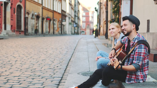 Young couple sitting on street in city