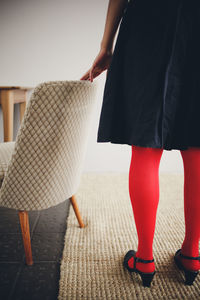 Low section of woman standing by chair at home