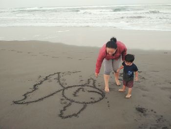 Rear view of mother and daughter on beach