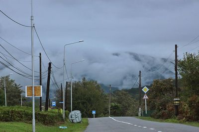 Road by trees against sky