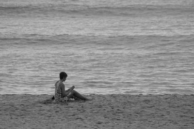 Man sitting on shore at beach