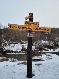 Information sign on snow covered field against sky