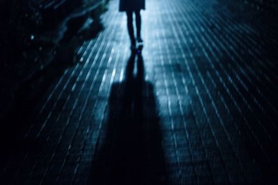 Low section of silhouette woman walking at night