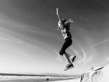 Low angle view of woman jumping on beach