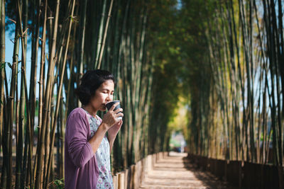 Woman drinking coffee standing at park