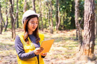 Young woman using mobile phone in forest