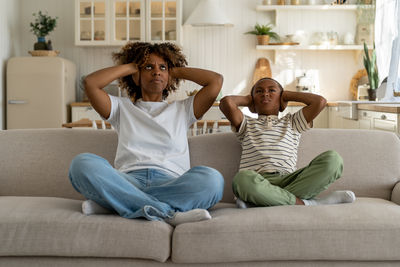 Friends using phone while sitting on sofa at home