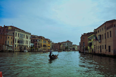 Canal amidst buildings in city against sky