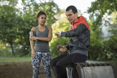 Man looking at wristwatch while woman touching arm band