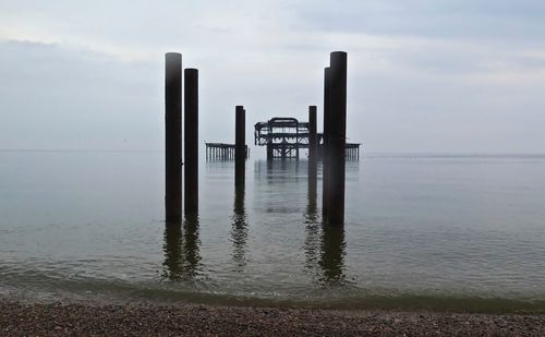 Metal  posts in sea against sky 