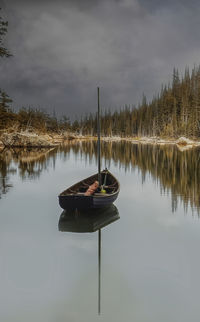 Man sitting by lake against sky