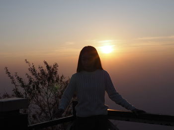 Woman standing against orange sky