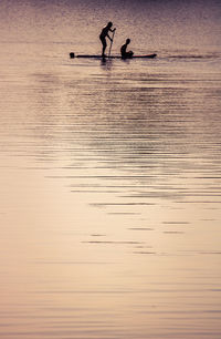 Silhouette people enjoying in lake during sunset