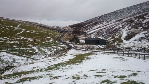 Houses on snow covered mountain against cloudy sky