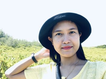 Portrait of young woman wearing hat standing against clear sky