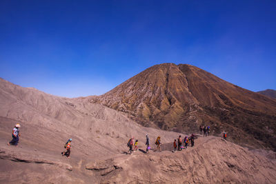 People on desert against clear blue sky