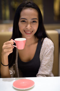 Portrait of young woman holding coffee cup